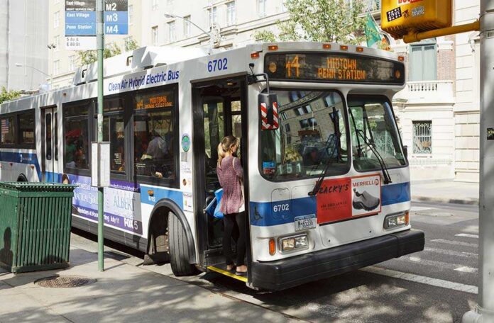 A woman boarding a clean air hybrid electric bus at a city stop