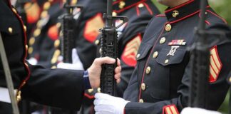 Marines in dress uniforms holding rifles during a ceremony