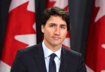 man in suit at podium with Canadian flags