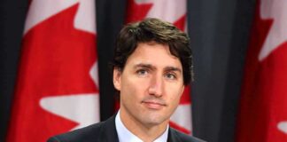 man in suit at podium with Canadian flags