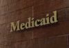 FBI Raids Ignite $500M Medicaid Meltdown Medicaid sign on a brown wooden wall
