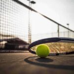 Tennis racket and ball on a court near the net