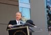 Bill Maher speaks at a podium during an outdoor event