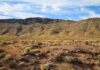 Wild Claims Collide With Boring Lab Results A vast desert landscape with a mountain range under a blue sky